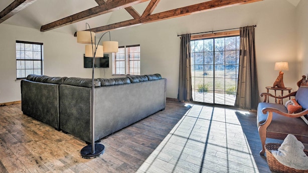 Een ruime woonkamer met een grote hoekbank, een vloerlamp en uitzicht door een groot raam.