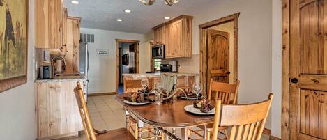 A dining area with a wooden table and chairs, a chandelier, and wooden cabinets.