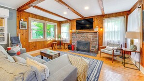 Un salon chaleureux avec des murs en bois, une cheminée en pierre, un grand téléviseur et des sièges confortables.