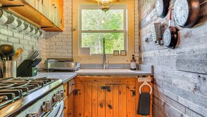Une cuisine rustique avec des meubles en bois, un poêle et une fenêtre donnant sur les arbres.