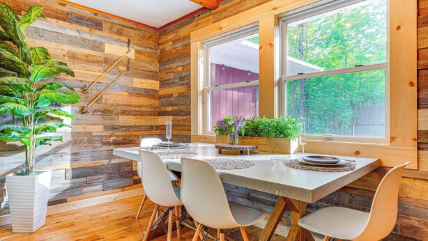 Un intérieur en bois avec une table à manger, des chaises et une grande fenêtre.