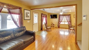 A living room with a leather sofa, wooden flooring, and a TV mounted on the wall. - Mtn-view Home w/ Deck, 2 Mi to Mickelson Trail! (Lead)