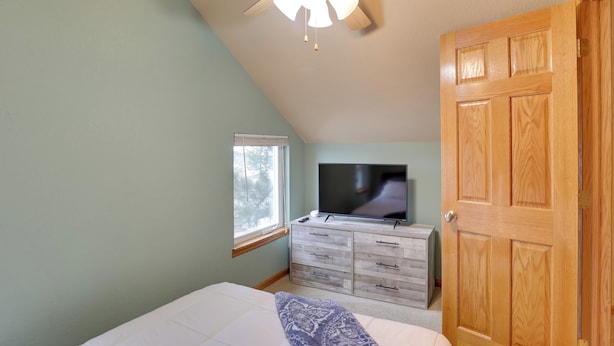 A bedroom with a bed, a TV on a dresser, a window, and a wooden door. - Mtn-view Home w/ Deck, 2 Mi to Mickelson Trail! (Lead)