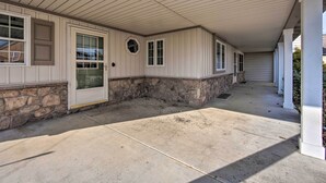 A covered porch with stone accents, a door, and windows. - Peaceful Bird in Hand Home w/ Farmland Views! (Bird In Hand)