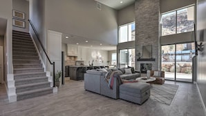 A spacious living area with a large gray sectional sofa, a staircase, and a kitchen in the background. - Spacious La Verkin Home: Near Zion Nat'l Park (La Verkin)