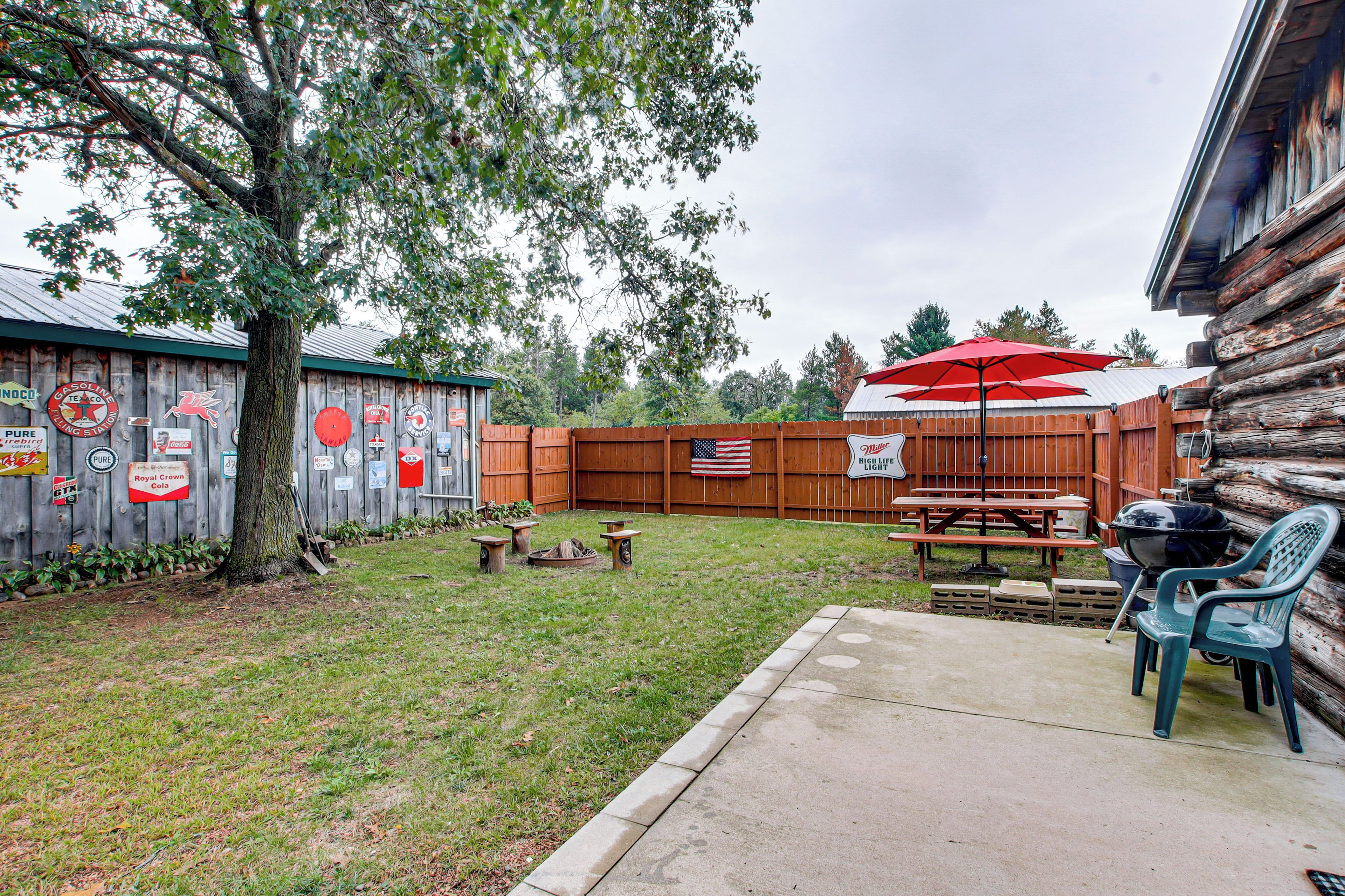 A backyard with a wooden fence, picnic tables, and a grill area.