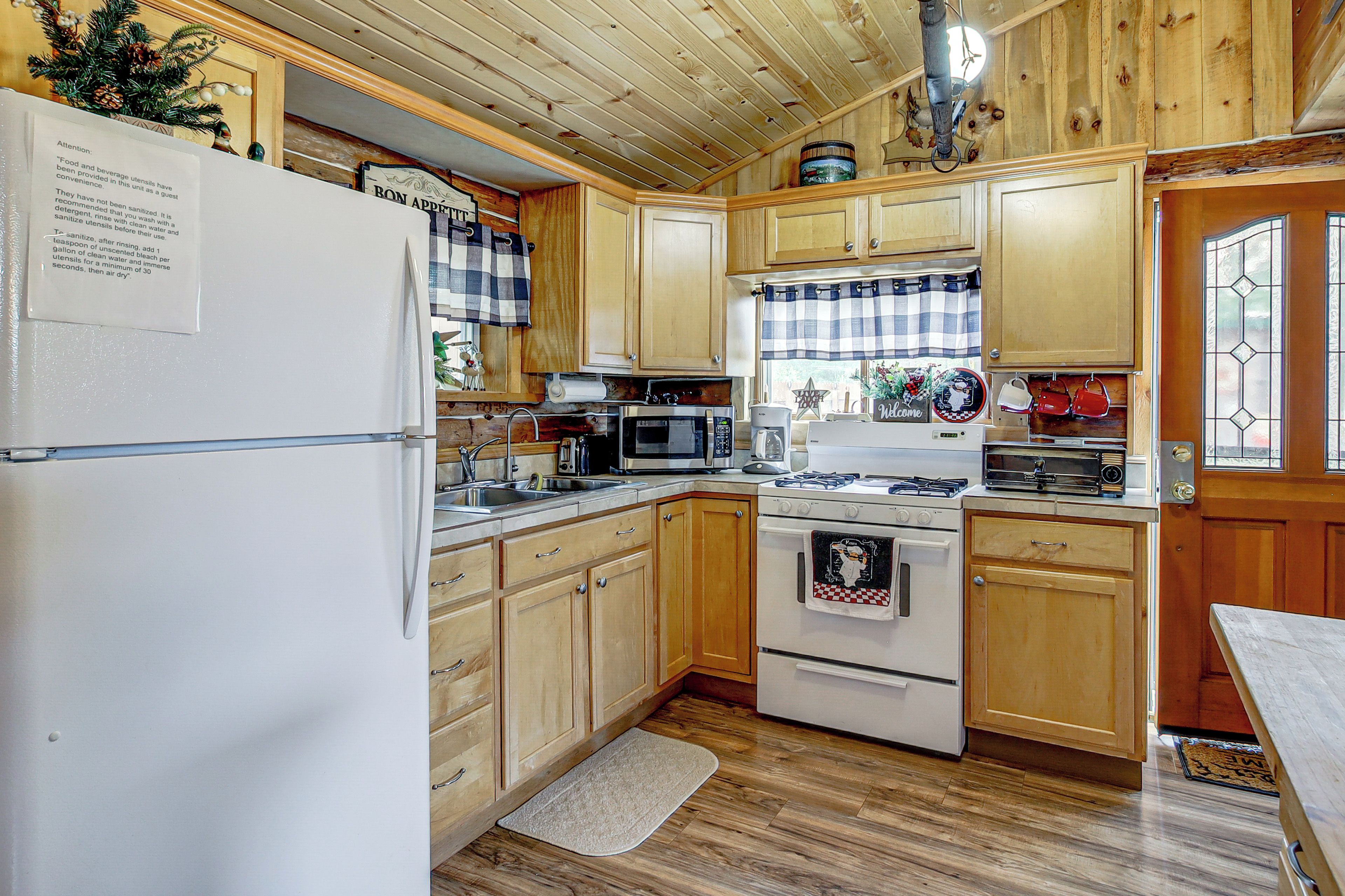 A kitchen with wooden cabinets, a refrigerator, a microwave, an oven, and a sink.