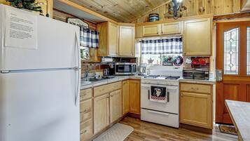 A kitchen with wooden cabinets, a refrigerator, a microwave, an oven, and a sink.