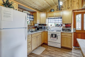 A kitchen with wooden cabinets, a refrigerator, a microwave, an oven, and a sink.