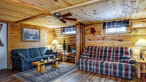 A log cabin interior with a sofa, armchair, and a small table with a lamp. - Arkdale Studio Cabin w/ On-site ATV Trails! (Arkdale)
