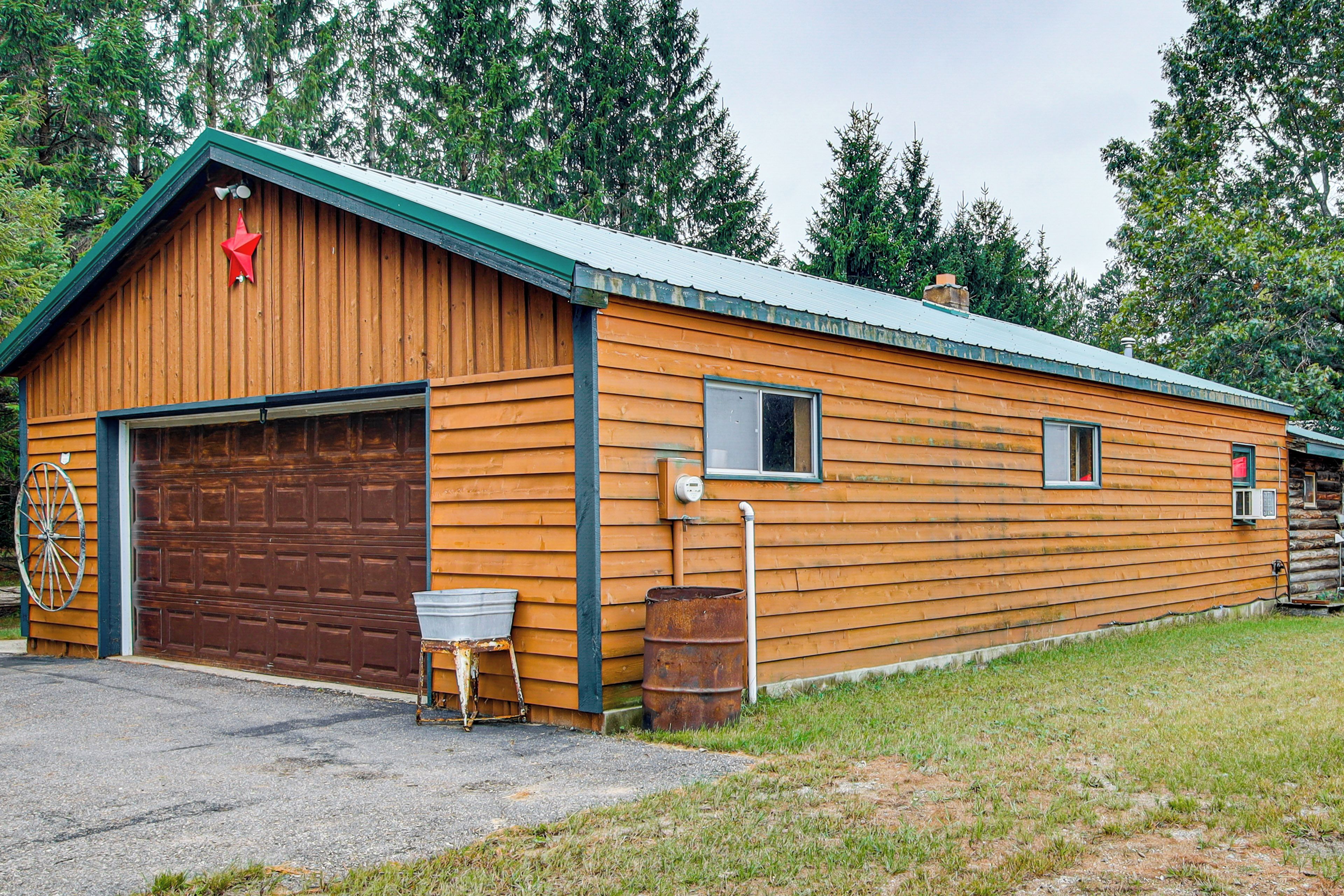 Un bâtiment en bois avec un garage, une petite fenêtre et un baril en métal.