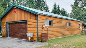 A wooden building with a garage, a small window, and a metal barrel.