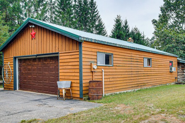 A wooden building with a garage, a small window, and a metal barrel.