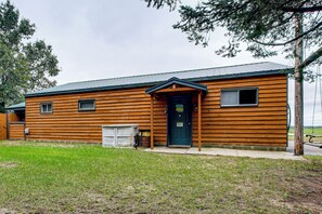 A wooden building with a dark door, a garage door, and a small window.