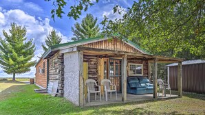 Un chalet rustique doté d’une véranda, de deux chaises et d’un canapé bleu.