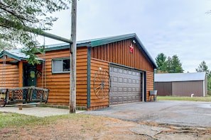 A wooden cabin with a garage, a swing set, and a metal wheel. - Arkdale Studio Cabin w/ On-site ATV Trails! (Arkdale)
