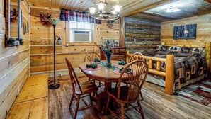 A log cabin interior with a dining area featuring wooden furniture, a chandelier, and a cozy fireplace. - Arkdale Studio Cabin w/ On-site ATV Trails! (Arkdale)