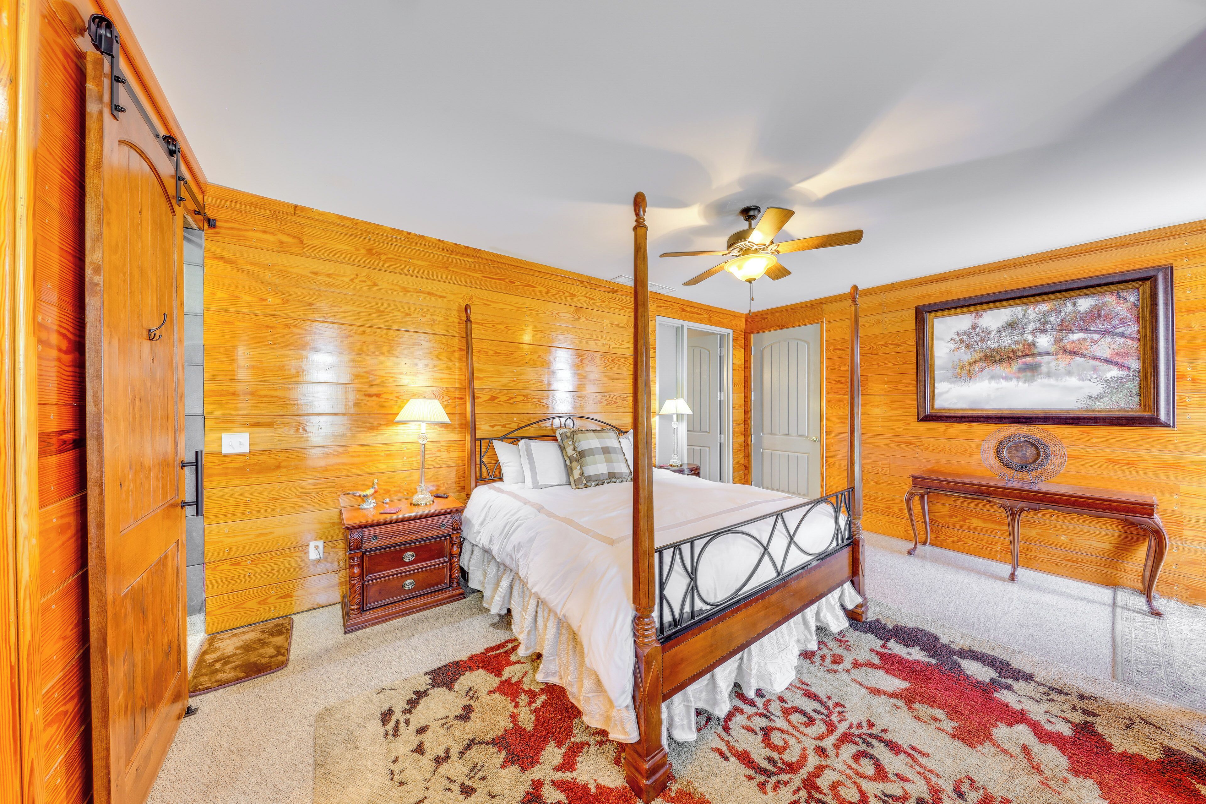 A four-poster bed with a wooden headboard, a ceiling fan, and a framed picture on the wall.