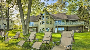 A large house with a balcony and multiple lounge chairs in the yard.