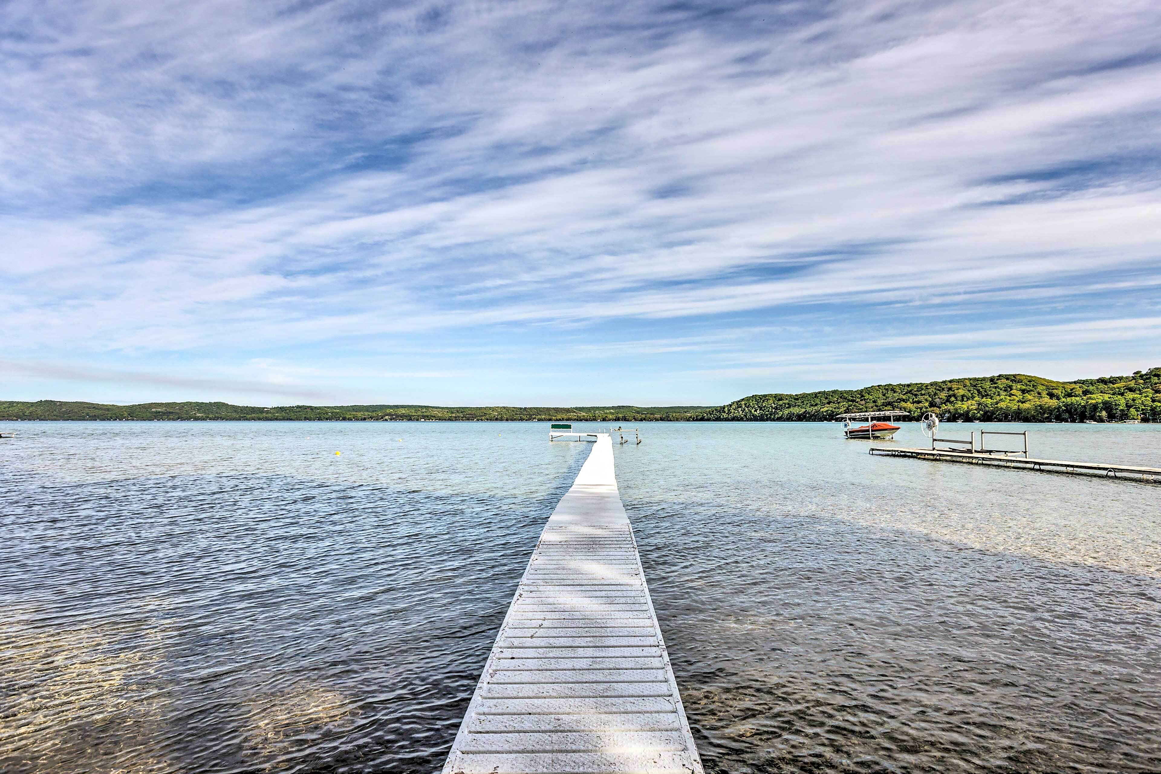 Eine hölzerne Pier, die sich über ruhiges Wasser erstreckt, mit einem Boot am Ende vertäut.