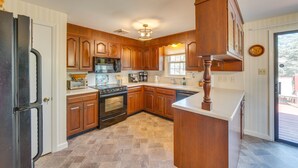 Una cocina con gabinetes de madera, un refrigerador, un horno, un microondas y un lavavajillas.