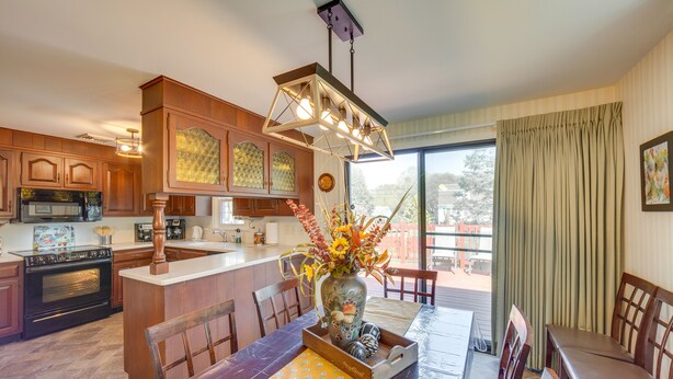 Una cocina moderna con armarios de madera, una isla central y un comedor con mesa puesta para cuatro.
