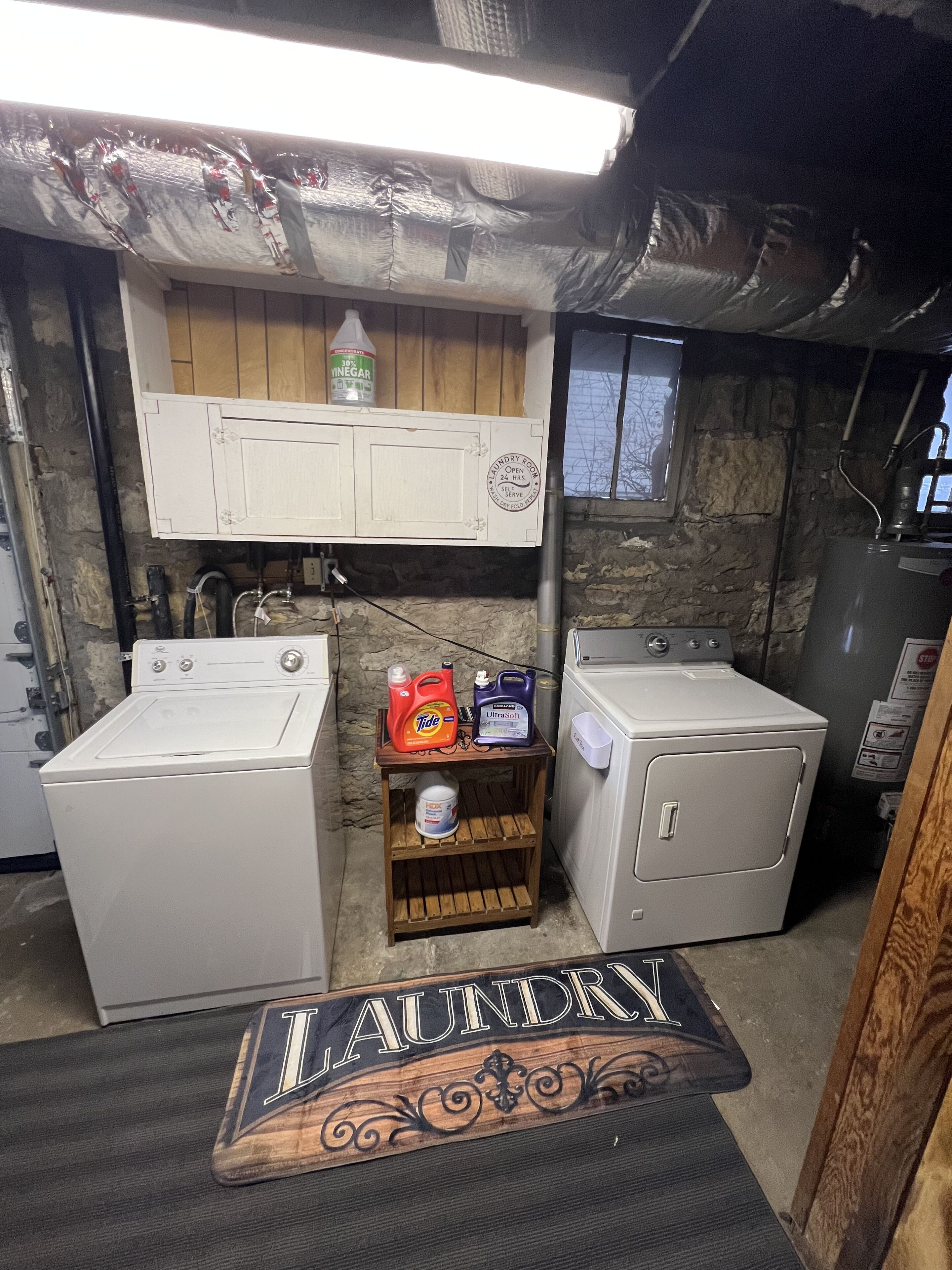 A laundry room with two washing machines, a shelf with detergent bottles, and a sign that reads "LAUNDRY".