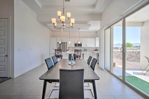 A modern kitchen with white cabinets, a stainless steel refrigerator, and a dining area with a long table and chairs. - Upper Valley El Paso Home w/ Hiking Access On-site (El Paso)