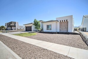 A modern residential area with houses featuring clean lines and neutral colors, a well-maintained lawn, and a gravel driveway. - Upper Valley El Paso Home w/ Hiking Access On-site (El Paso)