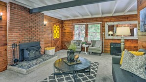 A cozy living room with a fireplace, a round coffee table, and a comfortable seating area. - Half-mi to Shaver Lake: Cabin w/ Wraparound Deck (Shaver Lake)