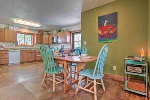 A kitchen with wooden cabinets, a dining table with chairs, and a painting on the wall.