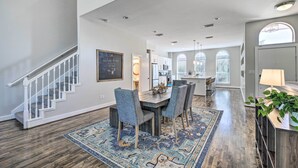 A spacious living area with a dining table, chairs, and a patterned rug. A staircase with white railings leads to another level. - 3-story Houston Townhome: 1 Mi to Minute Maid Park (Houston)