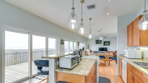 A kitchen with a large window, wooden cabinets, and a countertop with a toaster.