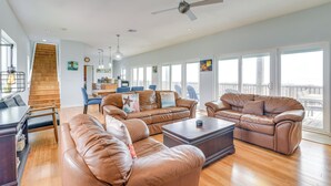 A spacious living room with leather sofas, a coffee table, and a staircase leading to an upper level.