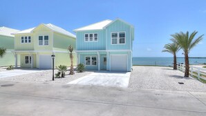 A two-story beachfront house with a garage, a driveway, and a white fence along the beach. - Seven Palms 3 Bedroom Home by RedAwning (Fulton)