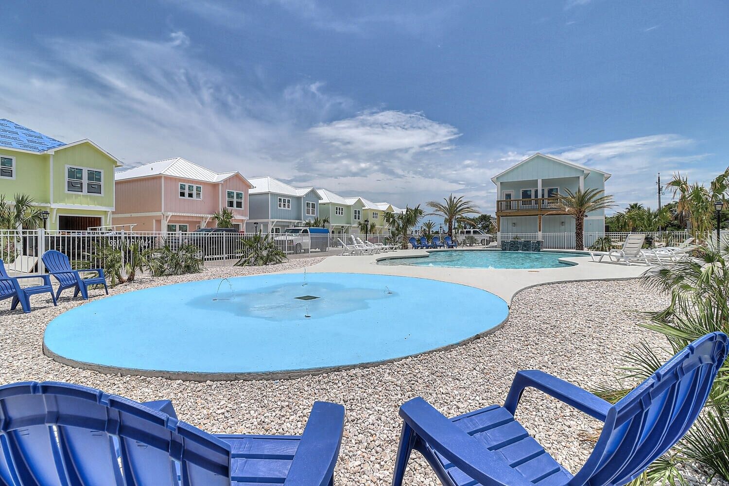 A resort with a large pool, multiple colorful buildings, and outdoor seating areas.