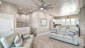 A modern living room with a beige sofa, striped pillows, and a ceiling fan. - Seven Palms 3 Bedroom Home by RedAwning (Fulton)