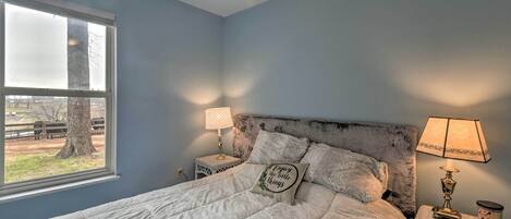 A bedroom with a bed, two bedside tables, a window, and a ceiling fan.