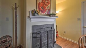 A living room with a fireplace, a coat rack, and a painting on the wall. - Cozy Rixeyville Cottage w/ Deck, Grill, & Stabling (Rixeyville)