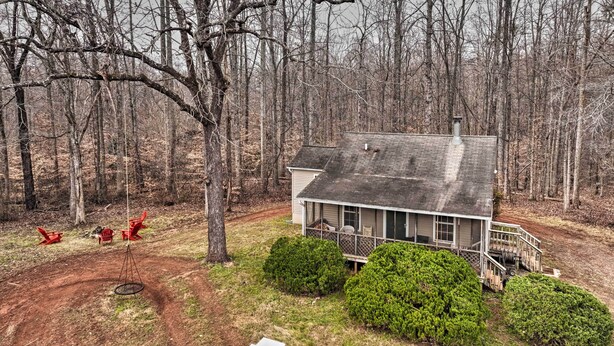 A cabin with a porch, surrounded by trees and a swing set. - Cozy Rixeyville Cottage w/ Deck, Grill, & Stabling (Rixeyville)