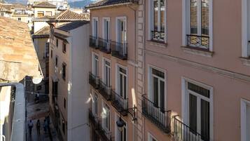 A narrow street with buildings featuring balconies and large windows.