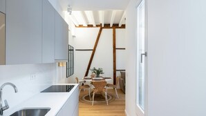 Una cocina moderna con un lavamanos doble, piso de madera y un comedor con mesa y sillas.