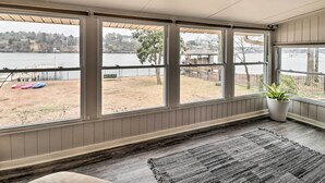 A room with large windows overlooking a lake, a wooden deck, and a potted plant. - Kayaks, Dock: Waterfront Escape on Lake Hamilton! (Hot Springs)