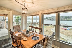 A dining area with a wooden table, chairs, and a view of a lake. - Kayaks, Dock: Waterfront Escape on Lake Hamilton! (Hot Springs)