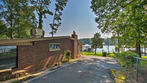 A brick building with a paved driveway leading to a covered area by a lake. - Kayaks, Dock: Waterfront Escape on Lake Hamilton! (Hot Springs)