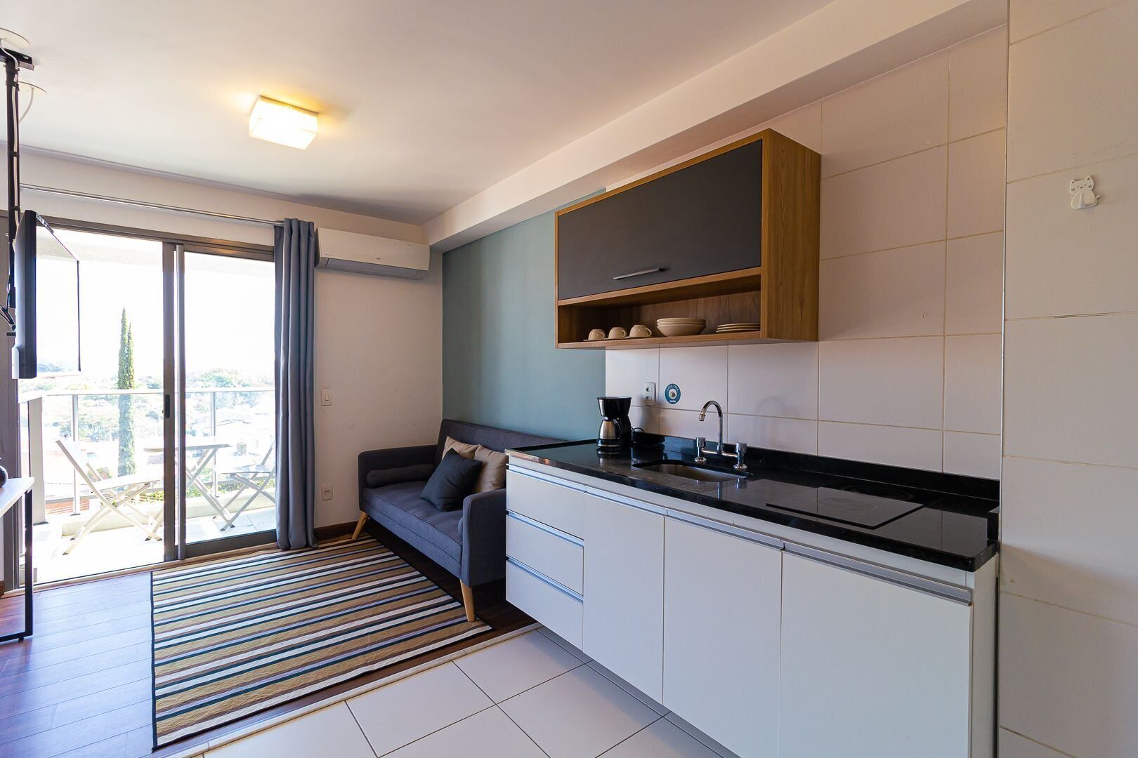 A compact kitchen with a built-in stove, a sink, and a wooden shelf above it.