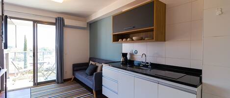 A compact kitchen with a built-in stove, a sink, and a wooden shelf above it.