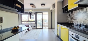 A modern kitchen with yellow cabinets, a black countertop, and a built-in oven.