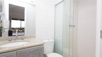 Ein modernes Badezimmer mit einer Duschkabine aus Glas, einem Waschbecken mit Marmorplatte und einer Toilette.