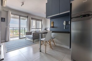 A modern kitchen with a stainless steel refrigerator, a dining area with a table and chairs, and a balcony with a view of the city.
